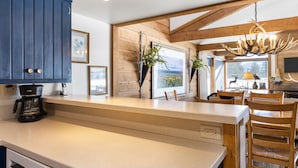 A kitchen with a large island, wooden cabinets, a coffee maker, and a chandelier.