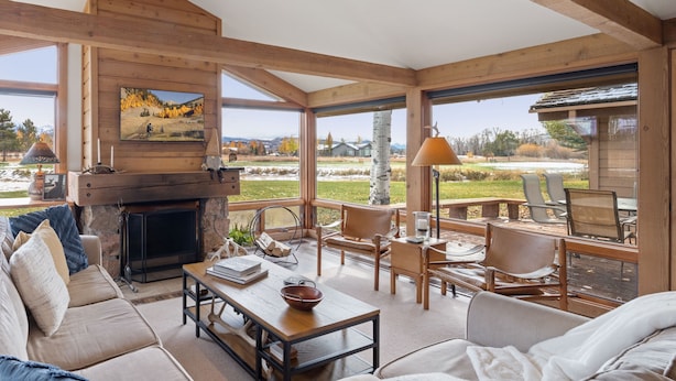 A spacious living area with a fireplace, comfortable seating, and large windows offering a view of the outdoors.