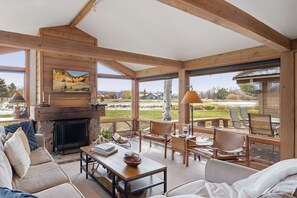 A spacious living area with a fireplace, comfortable seating, and large windows offering a view of the outdoors.