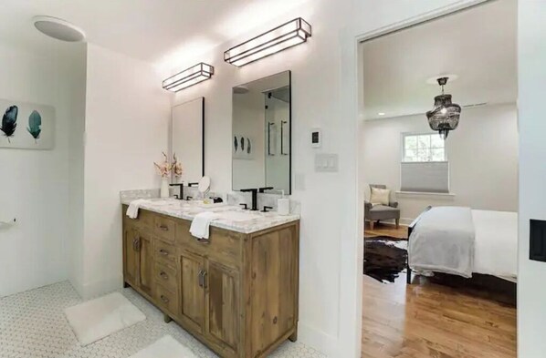 A modern bathroom with a wooden vanity, a large mirror, and a ceiling light fixture.