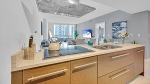 A modern kitchen with a large island, stainless steel range hood, and a view of high-rise buildings.