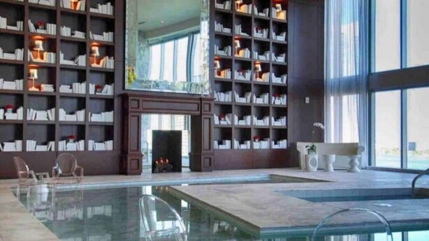 A library with bookshelves, a fireplace, and a swimming pool.