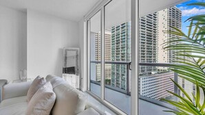 A modern apartment with a large window, a white sofa, and a mirror.