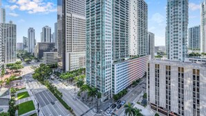 A high-rise urban area with modern buildings, a wide road, and palm trees.