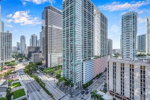 A high-rise urban area with modern buildings, a wide road, and palm trees.