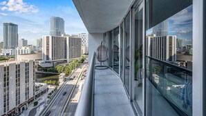 A balcony with a view of a cityscape, including tall buildings and a road.