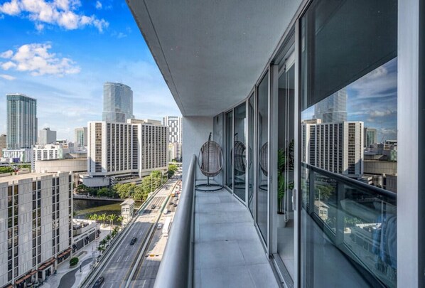 A balcony with a view of a cityscape, including tall buildings and a road.