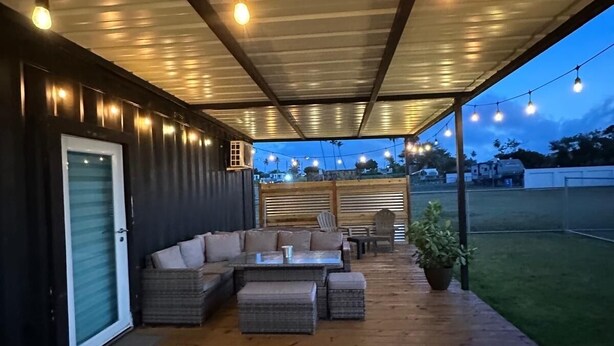 An outdoor covered patio with a wooden deck, a sofa set, and string lights.