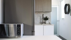 A modern kitchen with stainless steel appliances, a white countertop, and wooden cabinets.