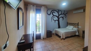 A bedroom with a bed, a desk, a TV, and a wall mural. - Posada Los Pedregales (El Granado)