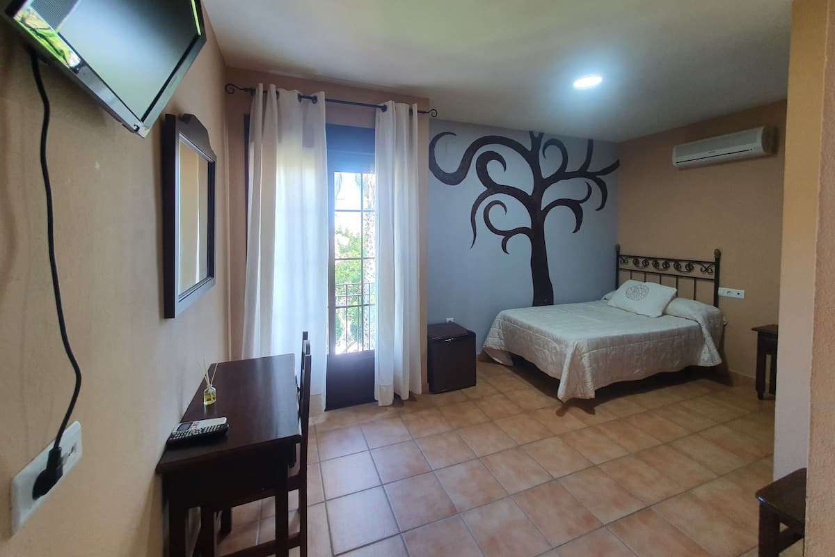 A bedroom with a bed, a desk, a TV, and a wall mural.