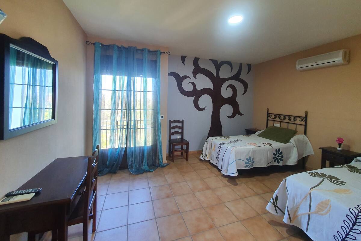 A bedroom with a bed, a chair, a desk, and a window with curtains.