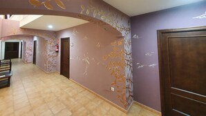 A hallway with a curved ceiling, a fire extinguisher, and a wooden bench. - Posada Los Pedregales (El Granado)