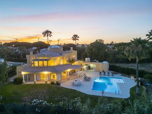 Una villa moderna con piscina, zona de estar exterior y jardín cuidado.