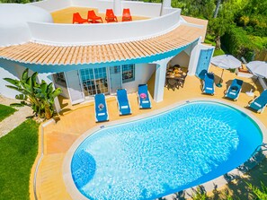 A modern poolside area with a pool, lounge chairs, and a dining area.