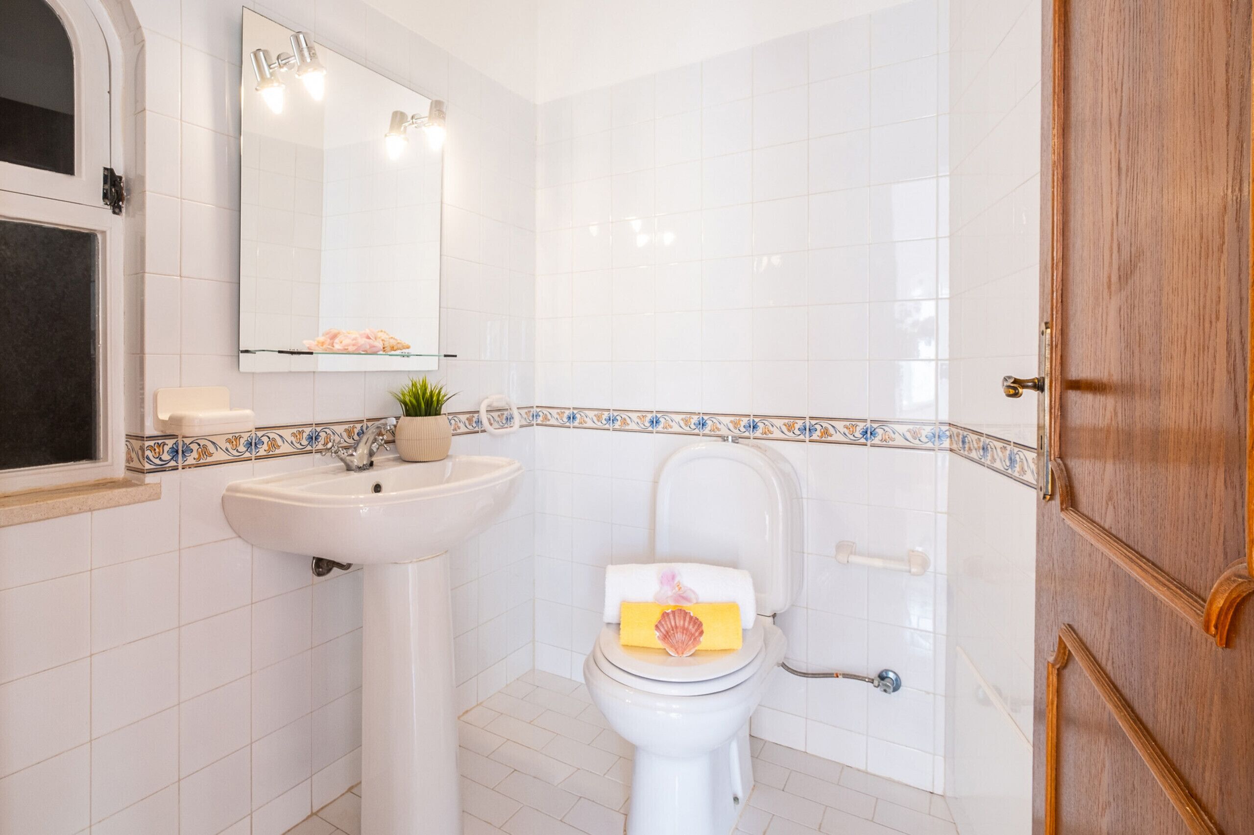 Een badkamer met een wit wastafelmeubel, een toilet en een spiegel.