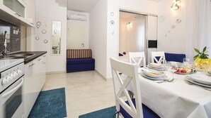A modern kitchen with a stove, sink, and a dining area with a table set for two. - Apartment in Zaton (Zadar) with Seaview, Balcony, Air condition, WIFI (685-2) (Nin)