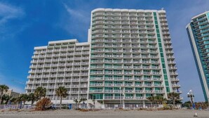Ett hotell med flera våningar och balkonger, beläget nära en strand.