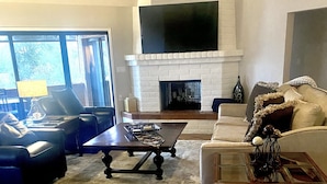 Un salon avec une cheminée, un canapé, une table basse et un téléviseur fixé au mur.