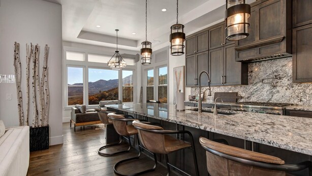 A modern kitchen with a large island, bar stools, and a view of the mountains.