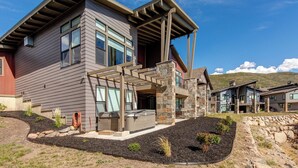 A modern two-story house with a stone facade, large windows, and a covered outdoor area.