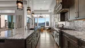 A modern kitchen with a large island, stainless steel appliances, and a view of the outdoors.