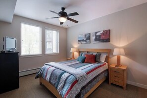 A bedroom with a bed, two bedside tables, a ceiling fan, and two windows with blinds. - Ski Condo with Mountain and Resort View - Fraser Crossing/Founders Pointe Select-Rated 4457 (Winter Park)
