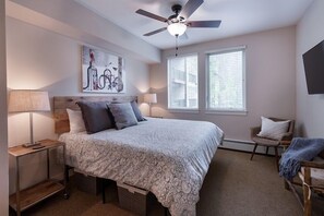 A bedroom with a bed, bedside lamps, a ceiling fan, a window, and a chair. - Ski Condo with Mountain and Resort View - Fraser Crossing/Founders Pointe Select-Rated 4457 (Winter Park)