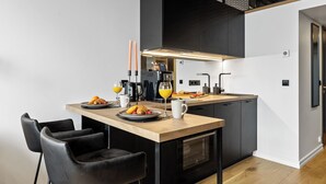 A modern kitchen with a wooden countertop, black chairs, and a coffee machine. - Bob W Tartu Old Town (Tartu)