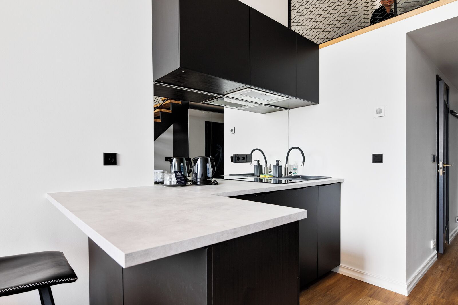 A modern kitchen with a central island, black cabinets, and stainless steel appliances.