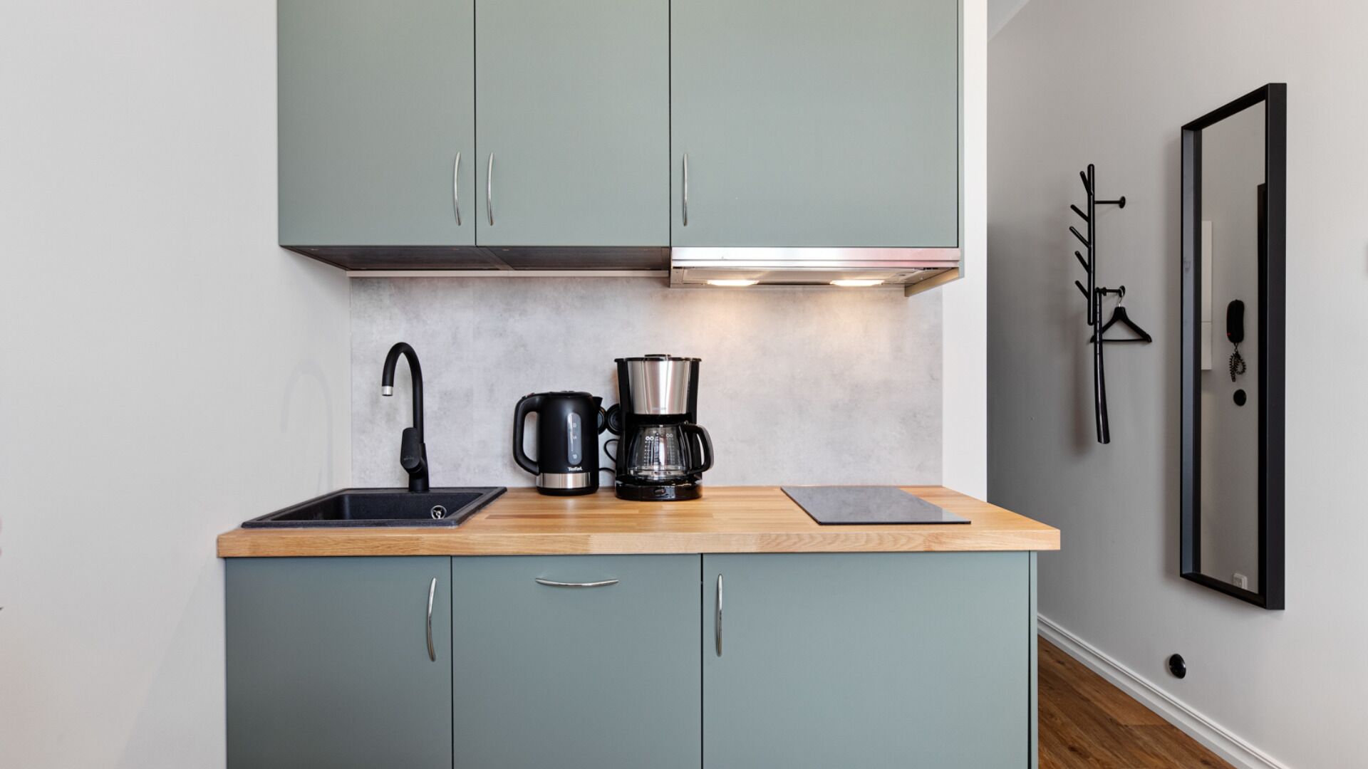 A compact kitchen with a sink, a coffee maker, and a small countertop.
