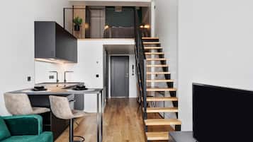 A modern apartment with a kitchen, dining area, and a loft bedroom.