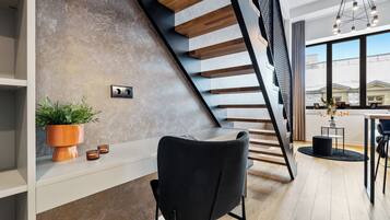 Un intérieur moderne avec un escalier, une chaise noire, une plante en pot et un coin repas offrant une vue agréable.