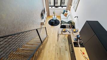 Een modern interieur met een houten vloer, een eethoek met tafel en stoelen, een bank en een zwarte kast.