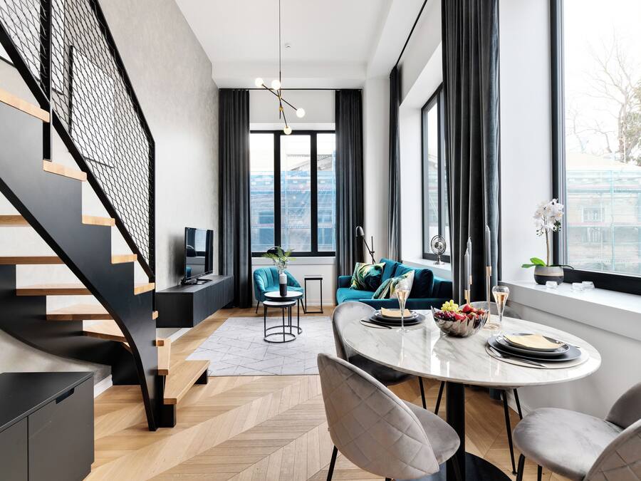 Un espacio habitable moderno con una escalera, un comedor y un conjunto de sofás.