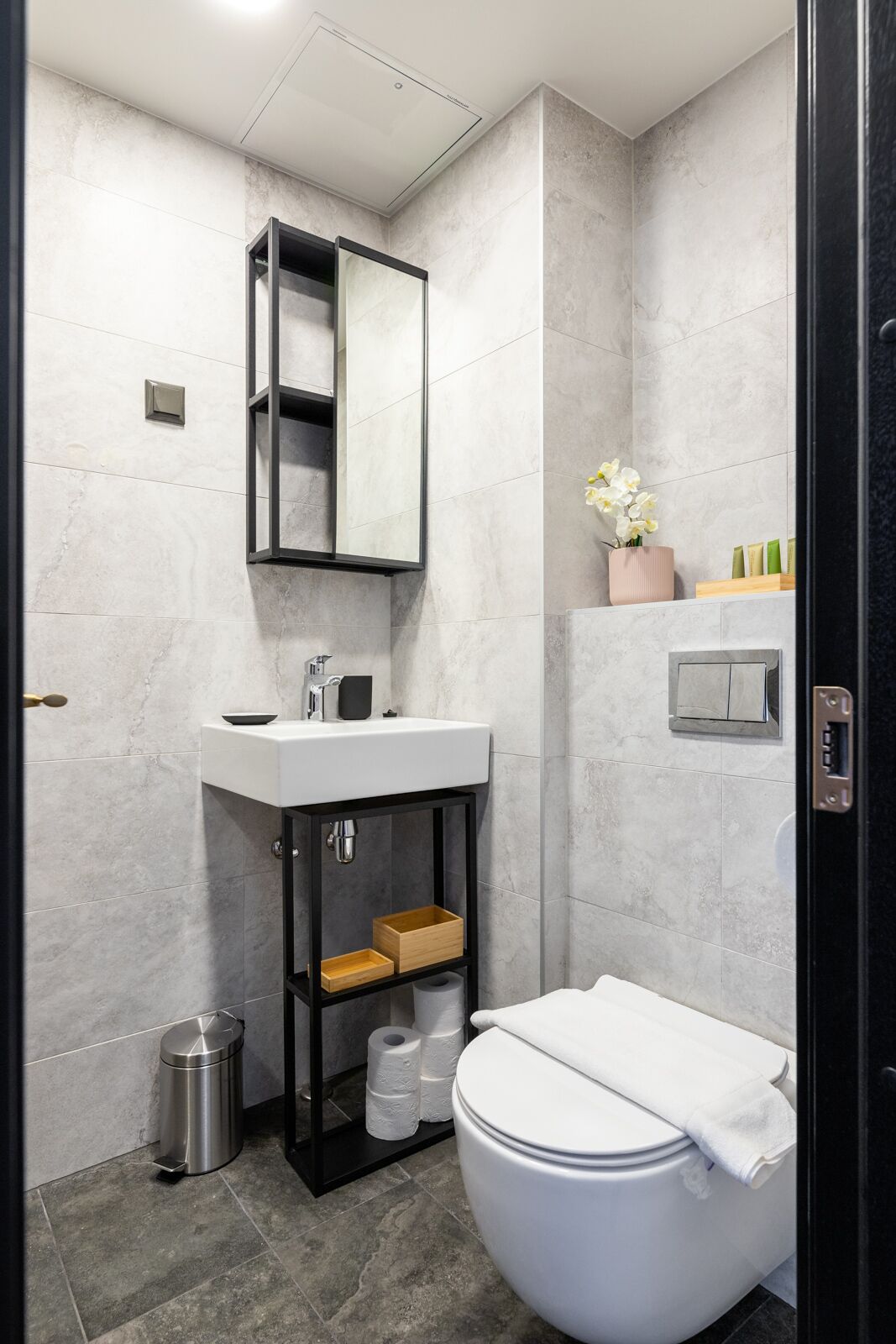 Ein modernes Badezimmer mit einem weißen Waschbecken, einem schwarzen Waschtisch und einer Toilette.