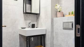 Ein modernes Badezimmer mit einem weißen Waschbecken, einem schwarzen Waschtisch und einer Toilette.
