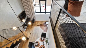 A modern loft-style room with a dining area, a bed with a black metal frame, and a view of the city through large windows. - Bob W Tartu Old Town (Tartu)