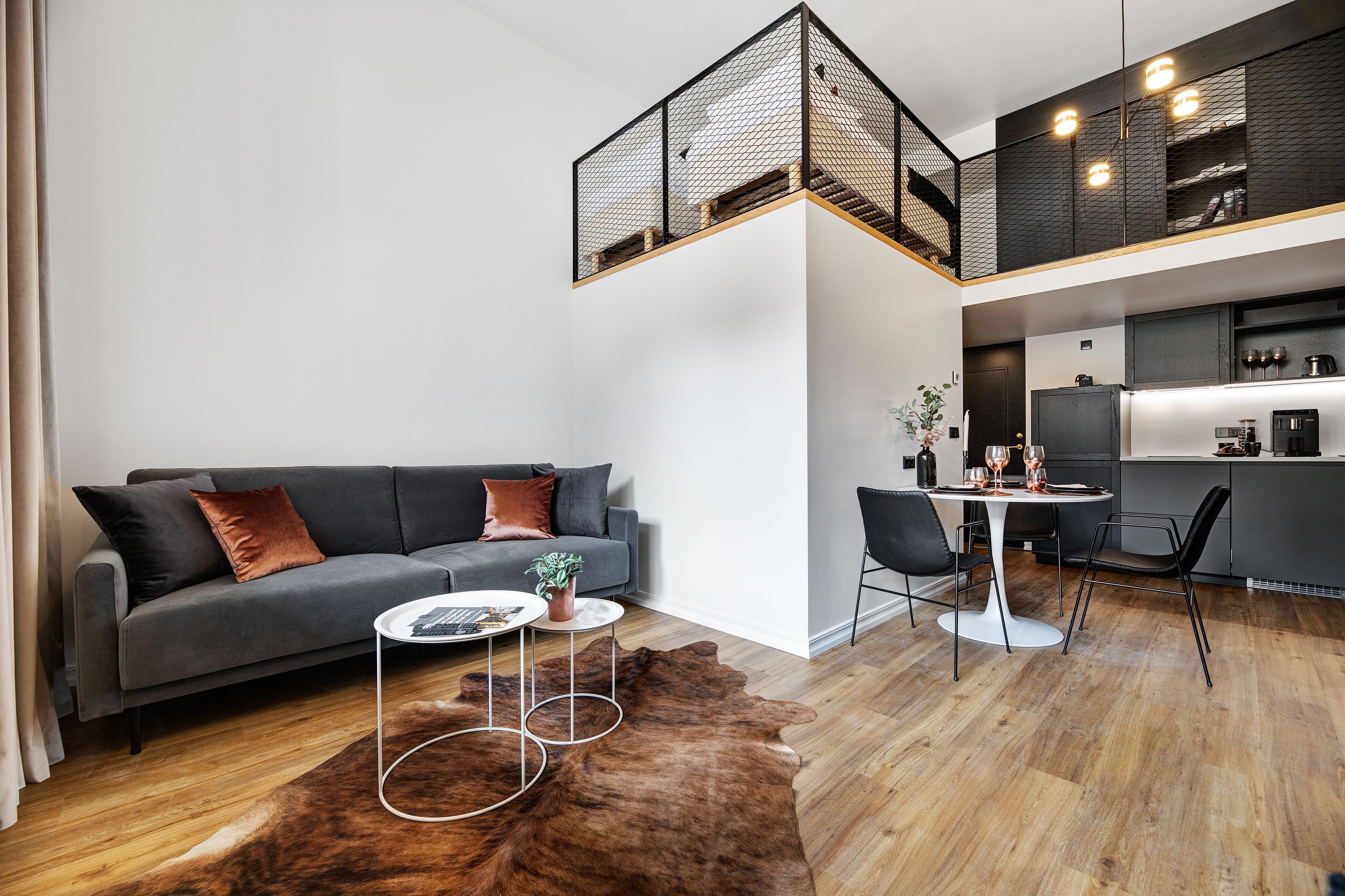 A modern living space with a grey sofa, a coffee table, and a dining area with a table and chairs.