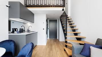A compact living space with a kitchen, dining area, and a staircase.