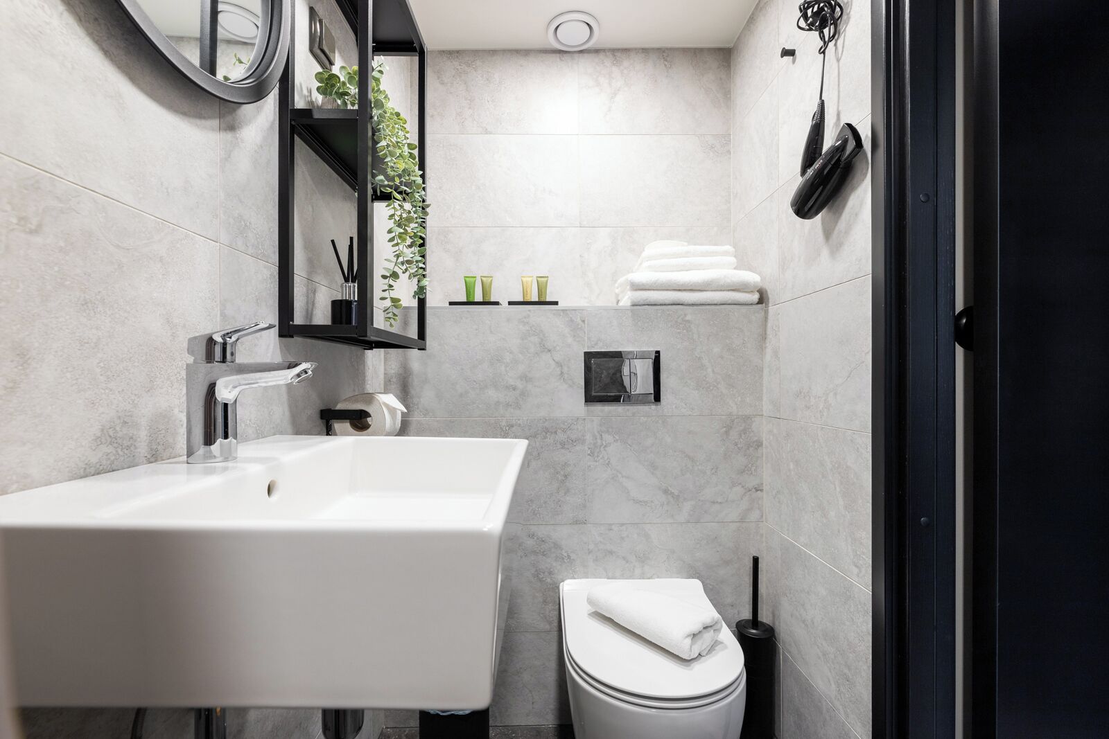 A modern bathroom with a large sink, toilet, and shower area.