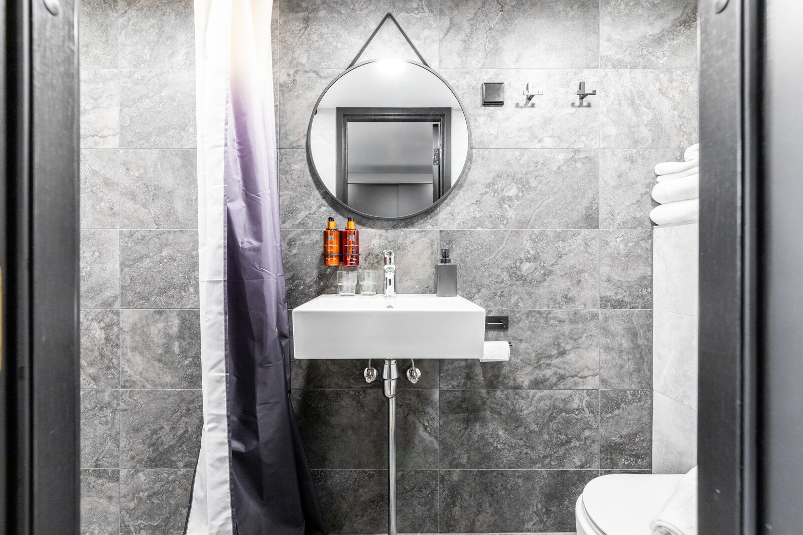A modern bathroom with a white sink, mirror, and shower curtain.