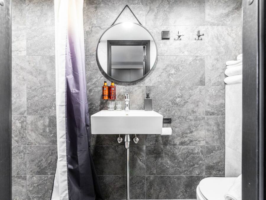 A modern bathroom with a white sink, mirror, and shower curtain.
