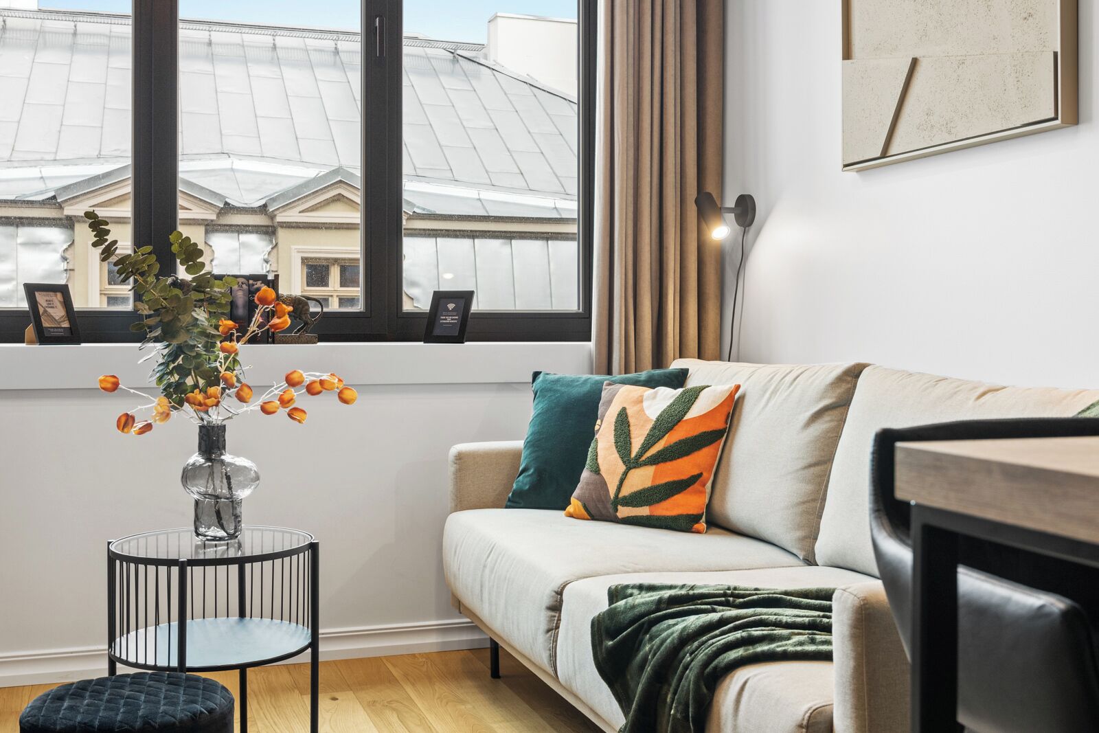 Ein modernes Wohnzimmer mit einem weißen Sofa, einem kleinen runden Tisch und einer Vase mit orangefarbenen Blumen.