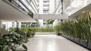 A modern building with multiple floors, large windows, and a central open space with potted plants. - Alure by Kukun (Mexico City)