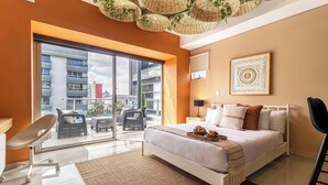 A modern bedroom with a large bed, a balcony with wicker furniture, and a city view. - Alure by Kukun (Mexico City)