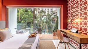 A modern hotel room with a bed, desk, and balcony with a city view. - Alure by Kukun (Mexico City)