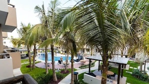 A pool area with palm trees, outdoor seating, and a modern architectural design. - Departamentos Ambar (Mazatlán)
