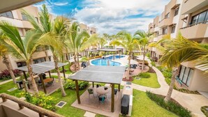 A resort courtyard with a central swimming pool, outdoor seating areas, and palm trees. - Departamentos Ambar (Mazatlán)