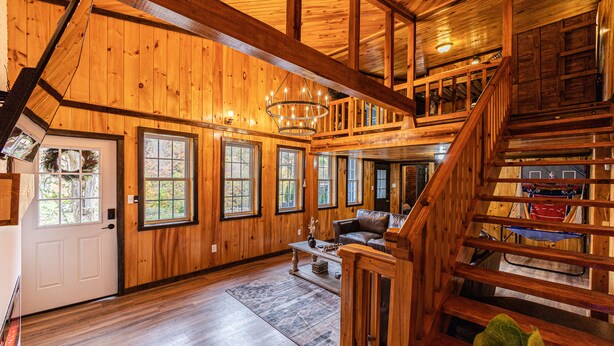 A spacious wooden cabin with a loft bedroom, a cozy living area with a fireplace, and a staircase leading to the upper level.